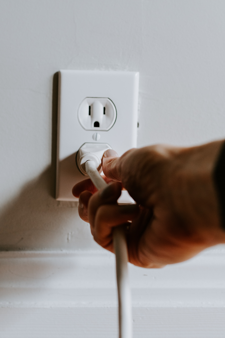Hand plugging a white cord into an outlet | © Unsplash / Kelly Sikkema