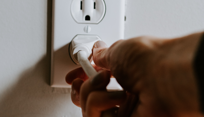 Hand plugging a white cord into an outlet | © Unsplash / Kelly Sikkema
