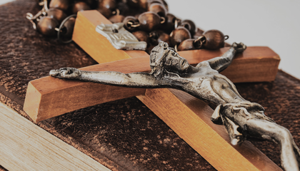 braunes Holzkreuz auf braunem Buch | © Unsplash / Myriam Zilles