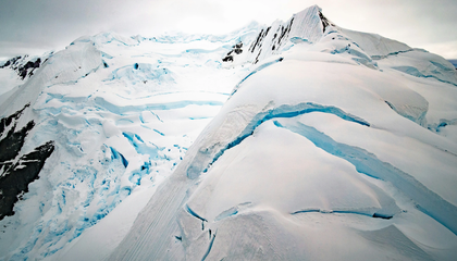 Aerial shot from helicopter over mountains near Paradise Bay, Antarctica.  Incredible, dramatic and deep crevasses illuminated with icy blue light from within. | © Unsplash / Rod Long